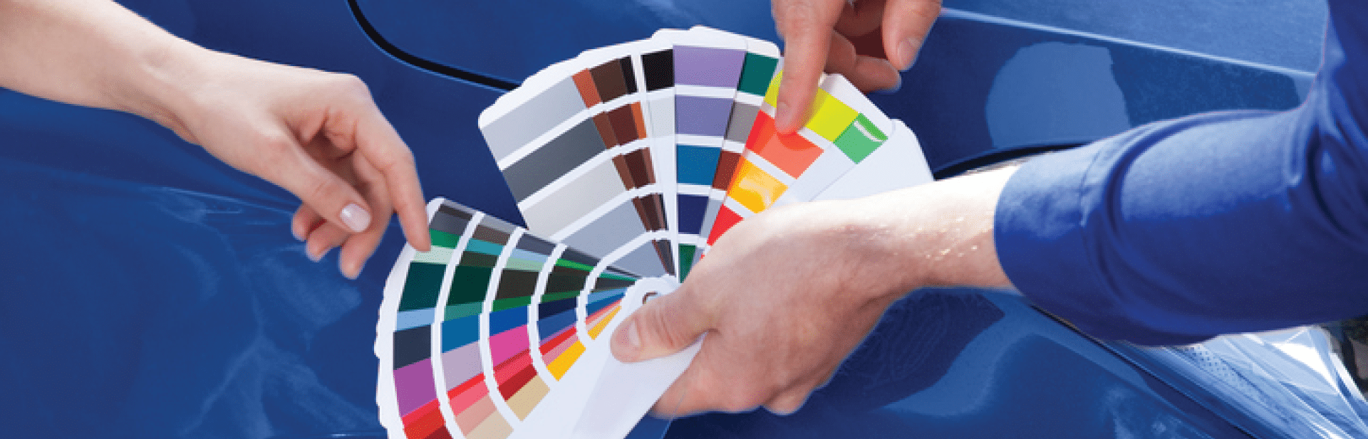 Cropped image of mechanic showing color samples to customer against car