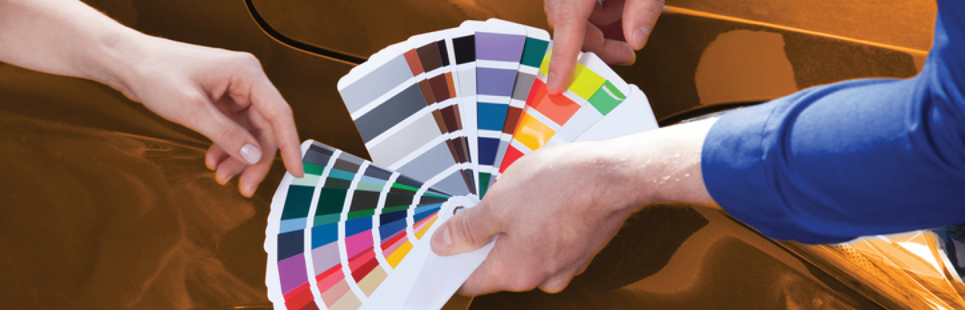 Cropped image of mechanic showing color samples to customer against car